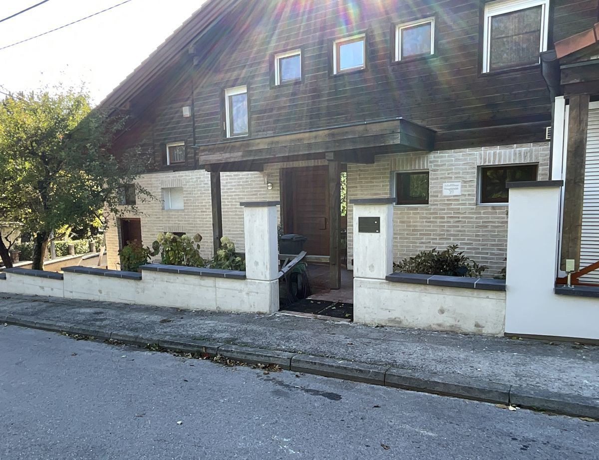 Ein großes Backsteinhaus mit einem weißen Zaun davor.