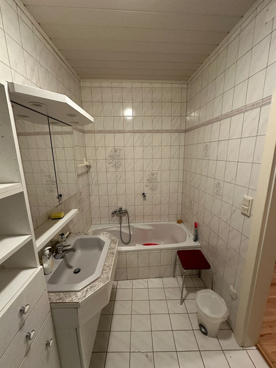 Ein Badezimmer mit Waschbecken, Badewanne, Spiegel und Mülleimer.