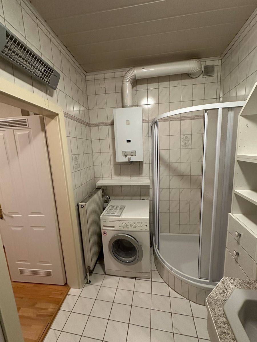 Ein Badezimmer mit Waschmaschine und Trockner und einer Duschkabine.