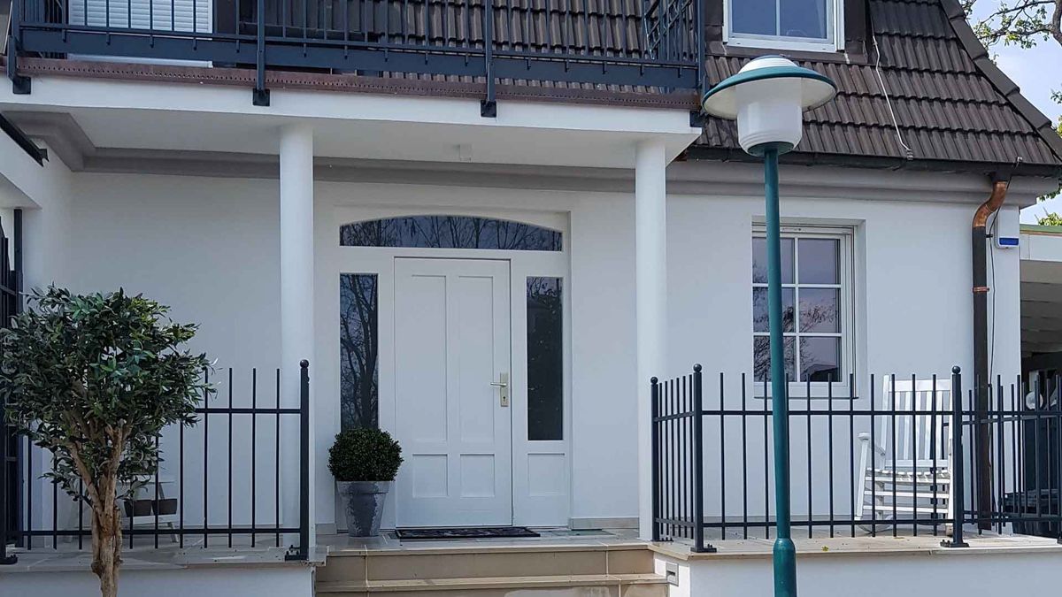 Ein weißes Haus mit einem blauen Laternenpfahl davor