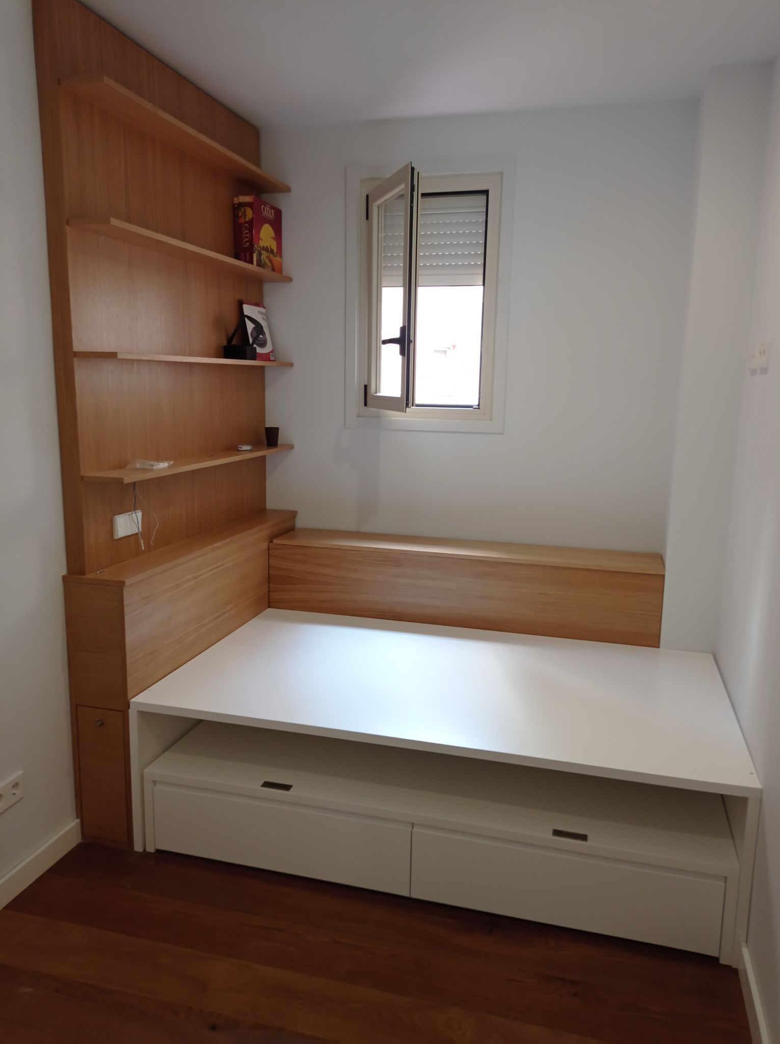 Un dormitorio con una cama, estanterías y una ventana.