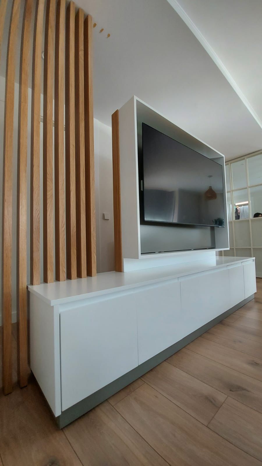 Una sala de estar con un centro de entretenimiento blanco y un televisor de pantalla plana.