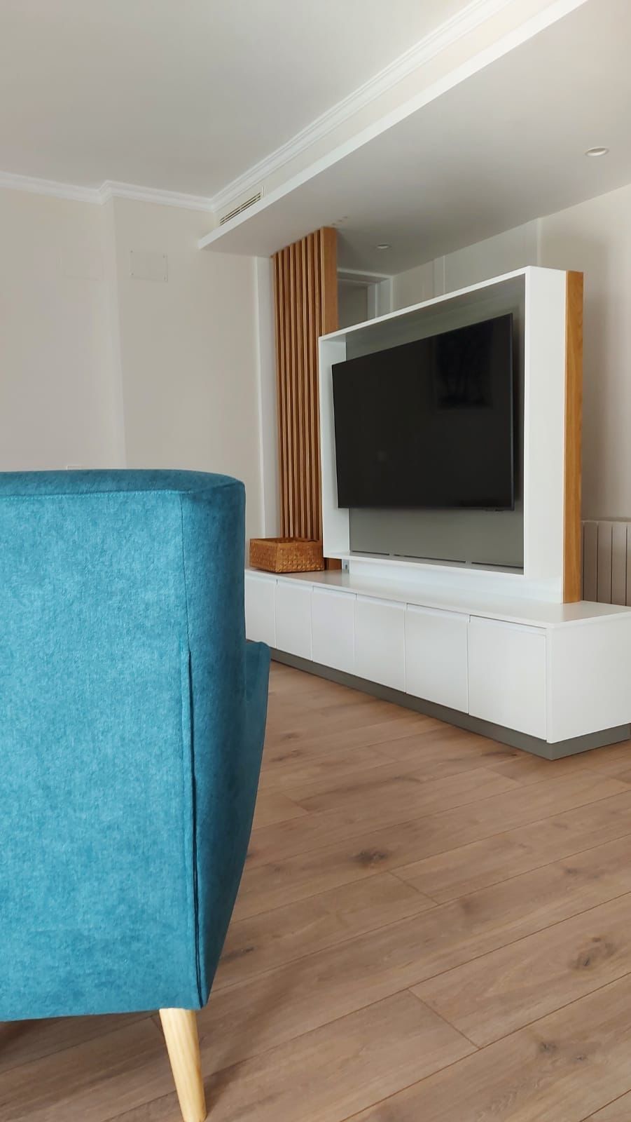 Una sala de estar con una silla azul y un televisor de pantalla plana.