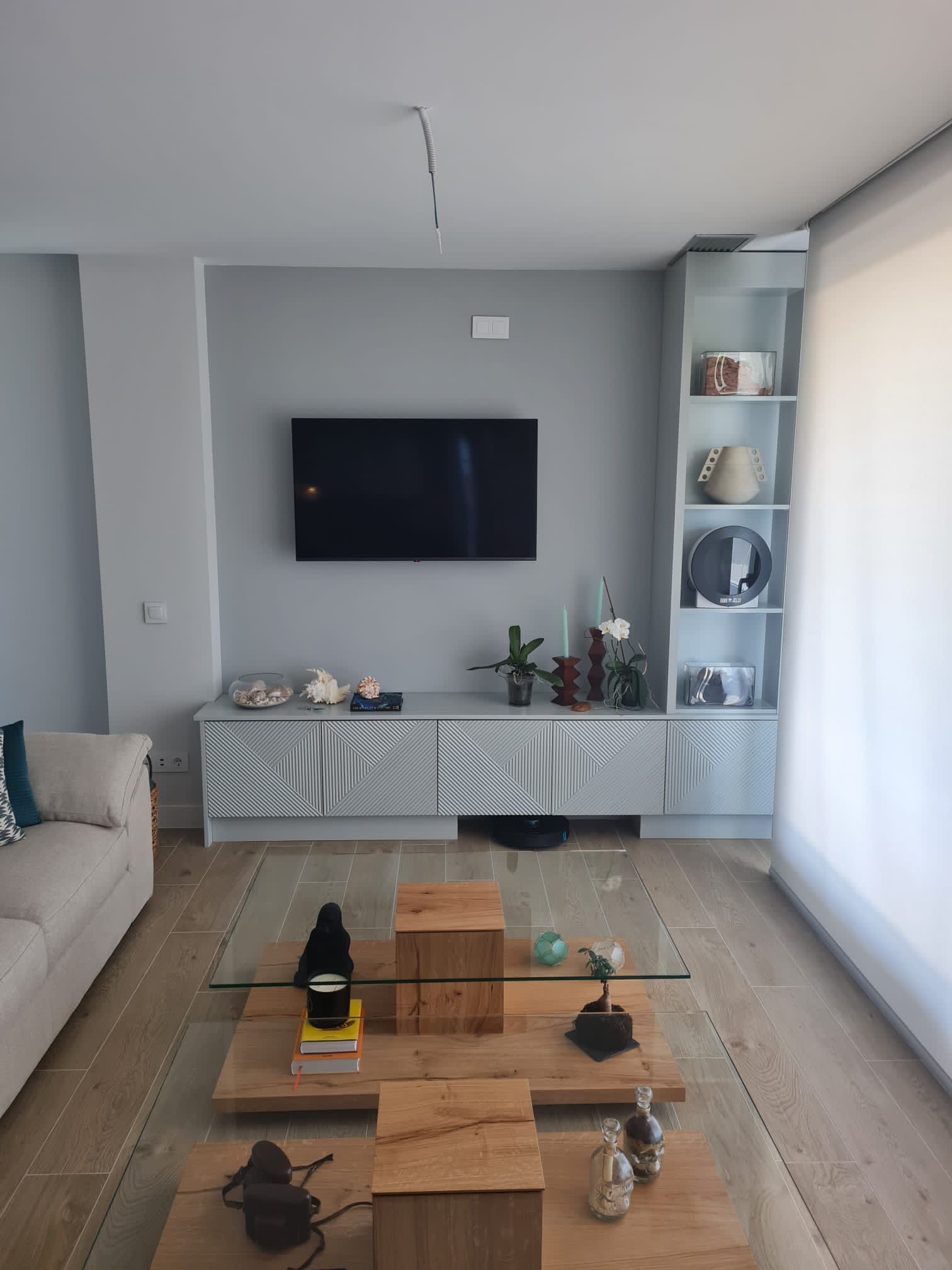 Una sala de estar con una mesa de café de cristal y un televisor de pantalla plana en la pared.