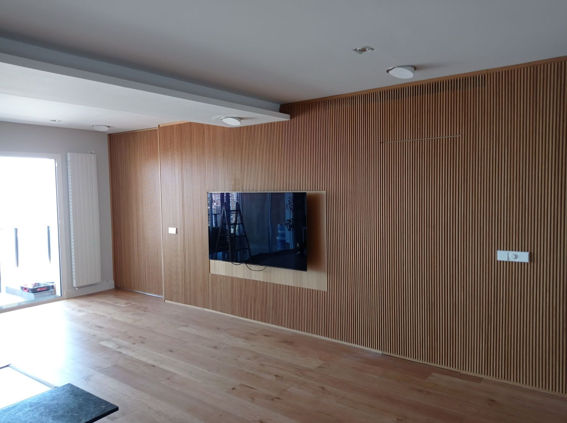 Una sala de estar con una pared de madera y un televisor de pantalla plana en la pared.