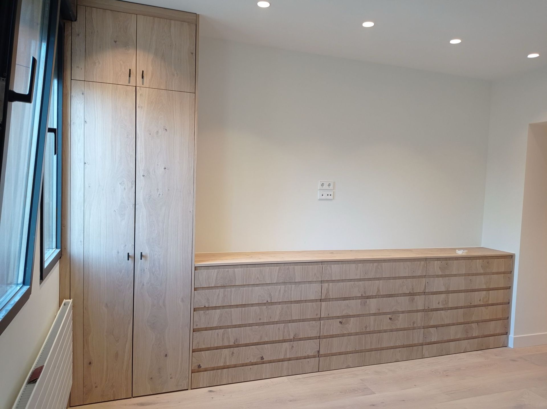 Una habitación con armarios y cajones de madera y una ventana.