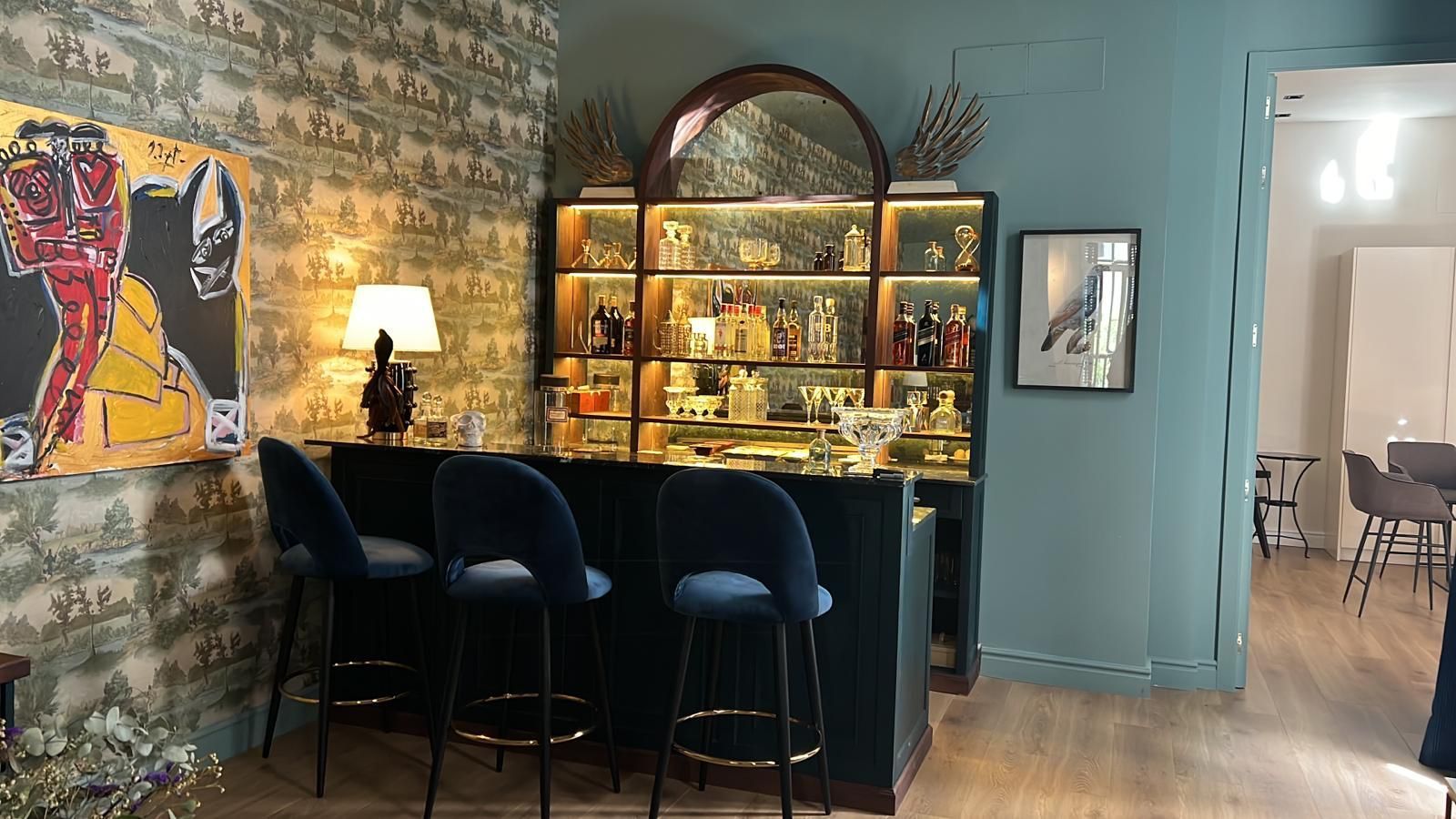 Una sala de estar con barra y taburetes y un cuadro en la pared.