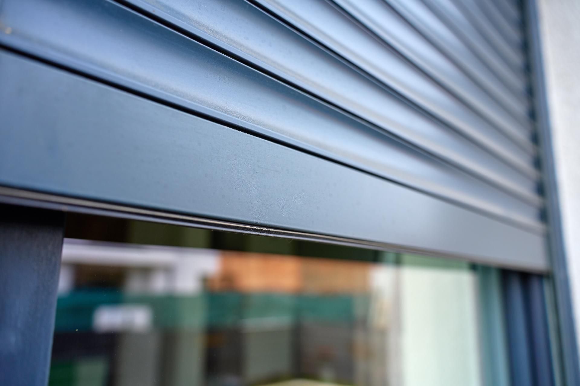 Nahaufnahme eines grauen Metallrollladens über dem Schaufenster eines Geschäfts