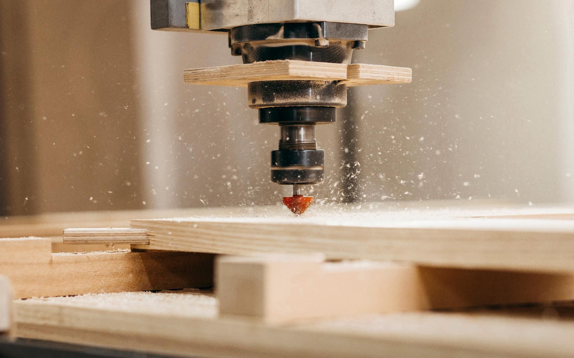 Eine CNC-Fräse schneidet in einer Werkstatt ein Holzbrett, während Sägemehl aufwirbelt