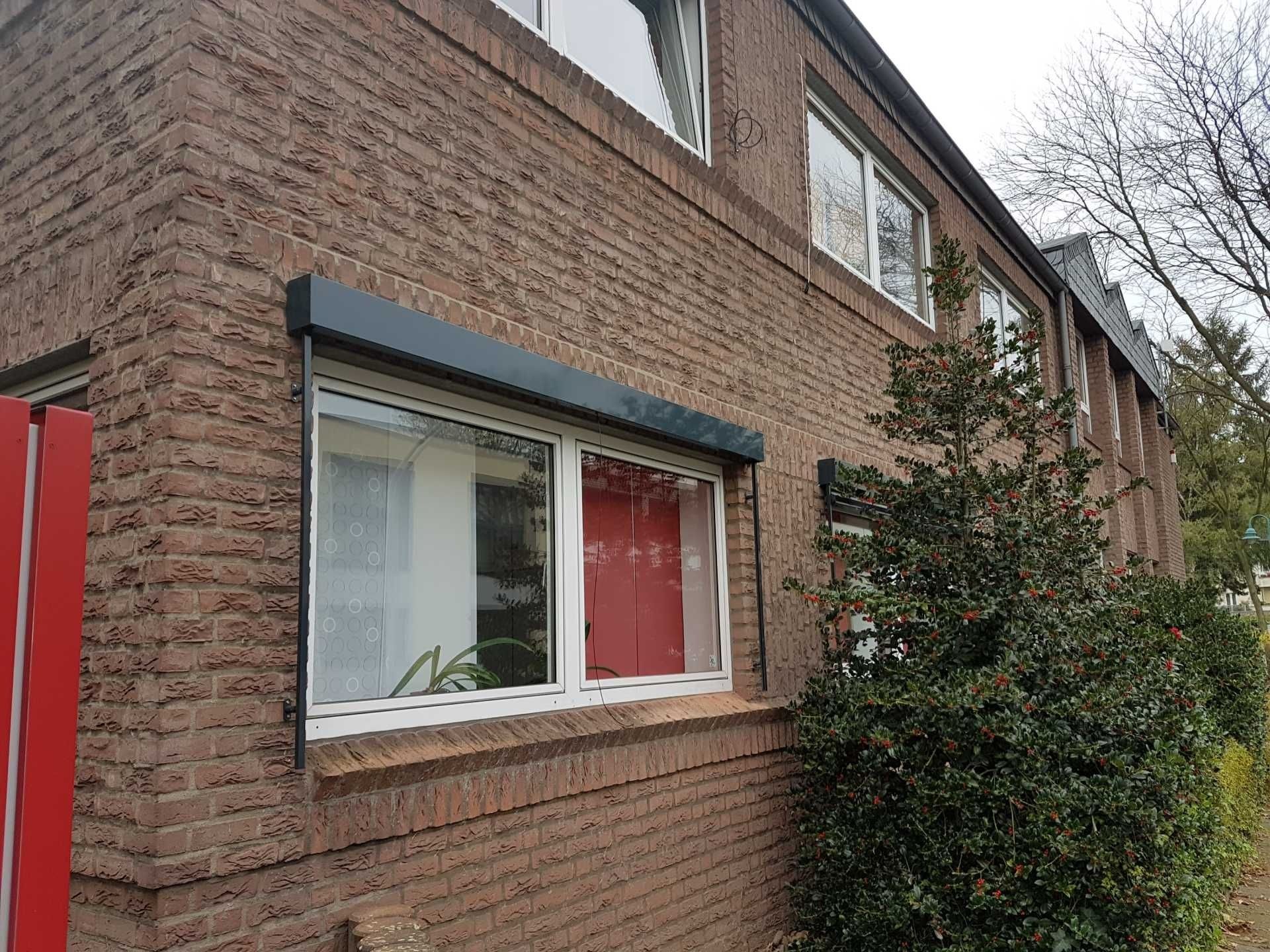 Außenansicht eines Backsteingebäudes mit einem Fenster, einer roten Verkleidung und einem Baum neben der Wand