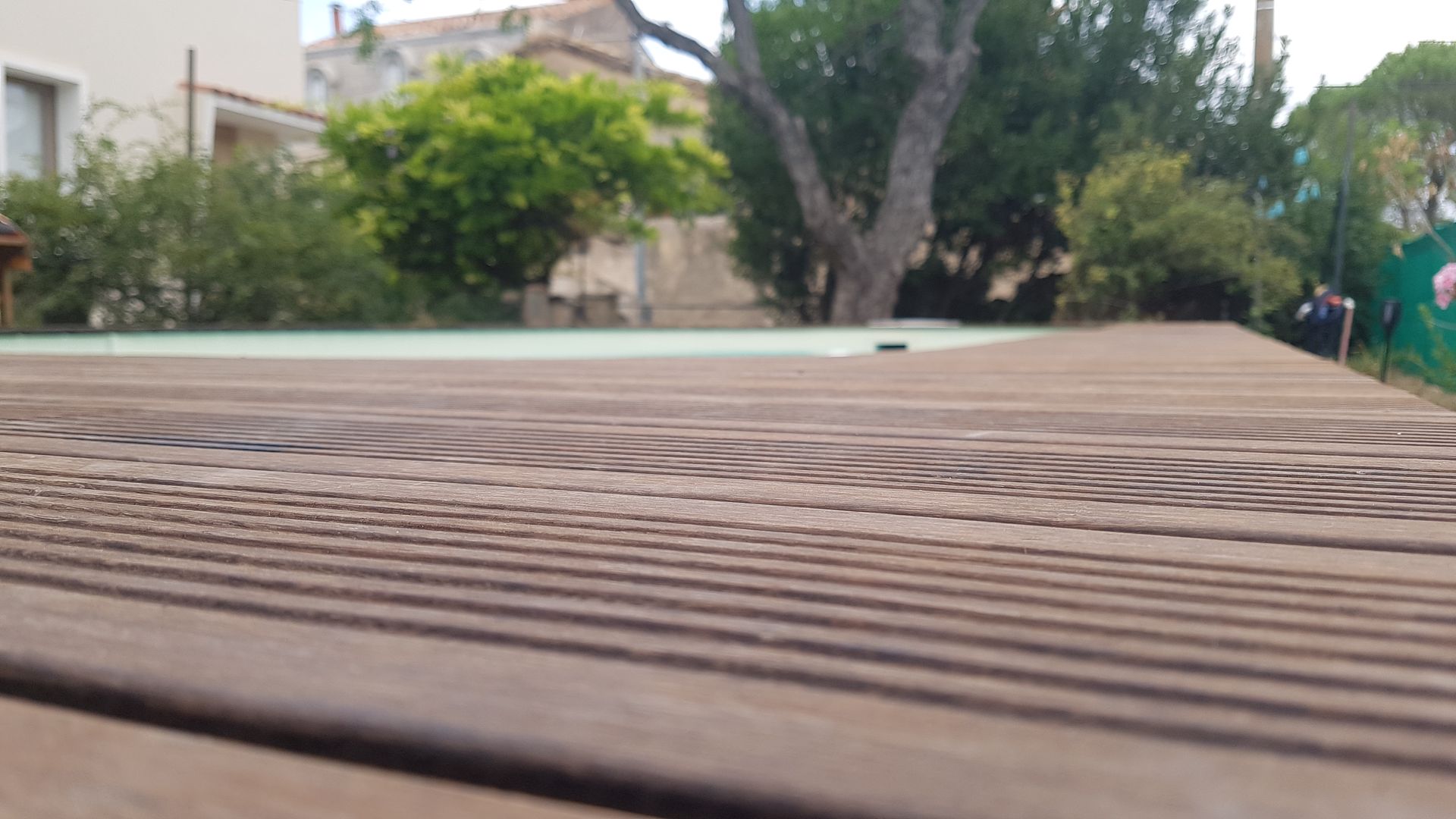 Une terrasse en bois autour d'une piscine.
