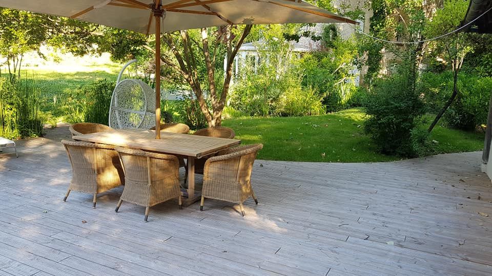 Une terrasse en bois avec un assortiment de meubles de jardin en osier.
