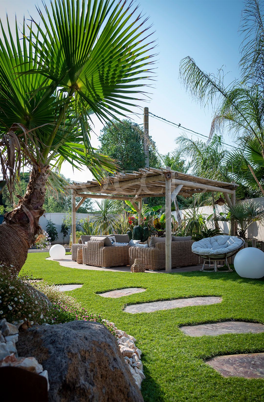 Paysage désertique avec une sculpture de cactus en métal entourée de rochers et de cactus.