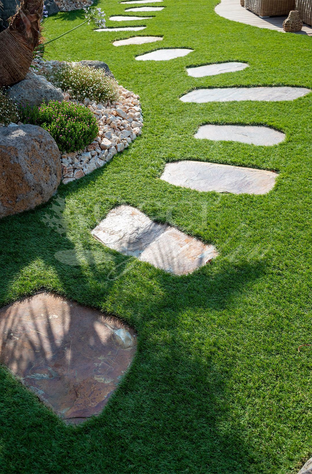 Espace détente extérieur tropical avec pergola, pelouse et pas japonais.
