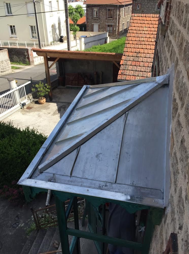 Toit en métal sur un petit porche à côté d'une maison, avec les bâtiments voisins en arrière-plan.