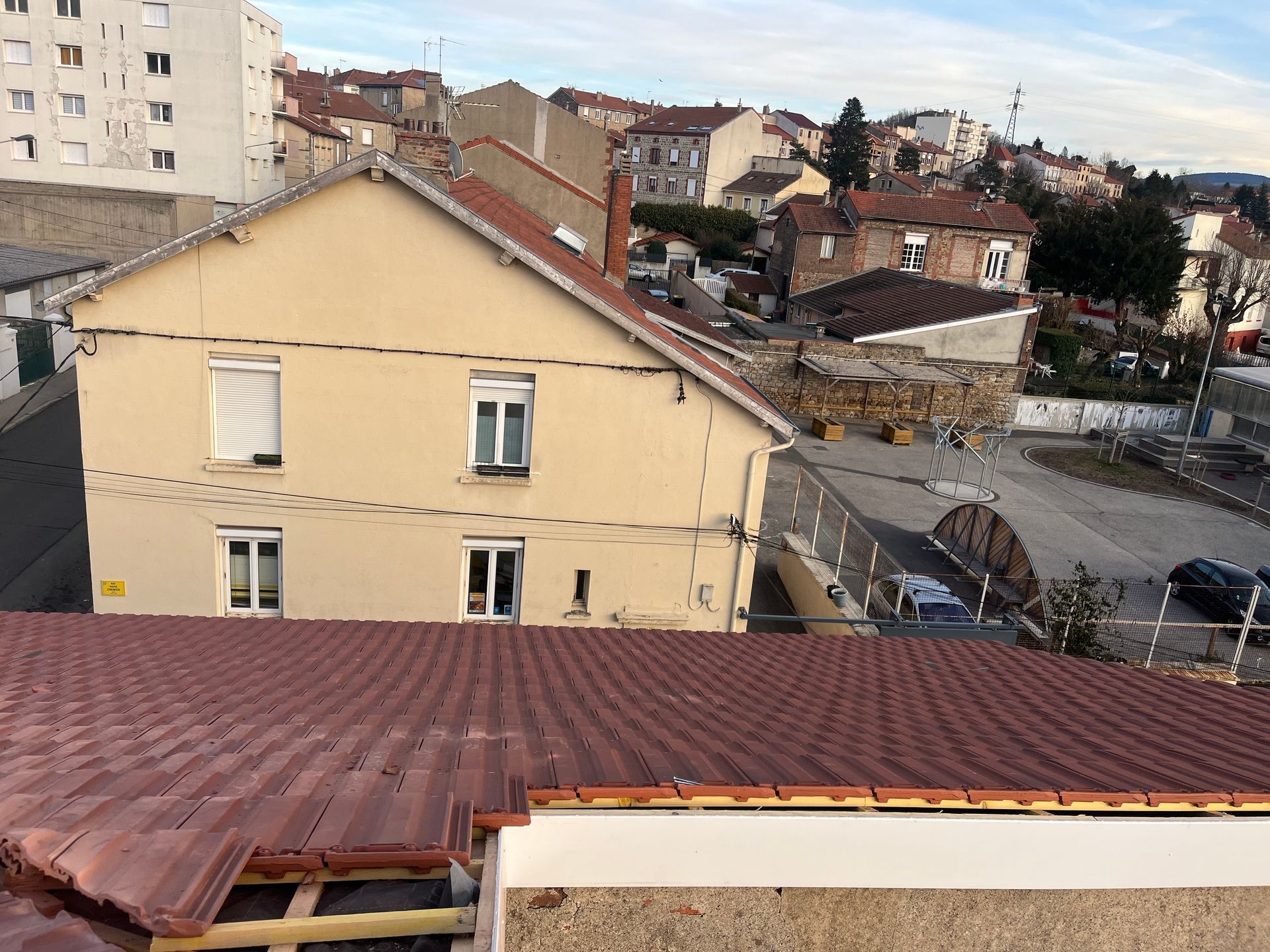 Vue depuis les toits de maisons beiges et de toits de tuiles rouges dans un quartier résidentiel.