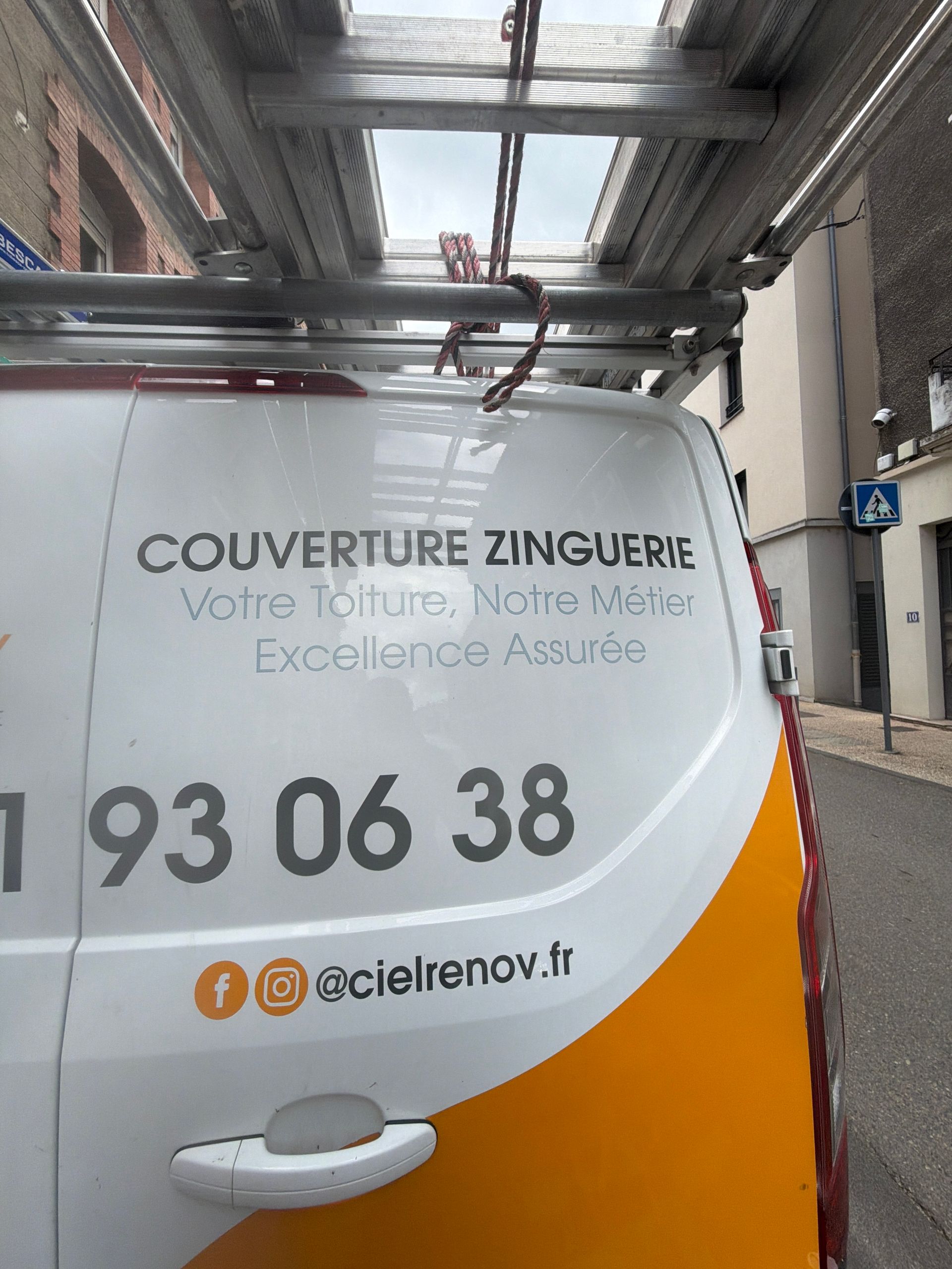 Une camionnette blanche avec les coordonnées de l'entreprise.