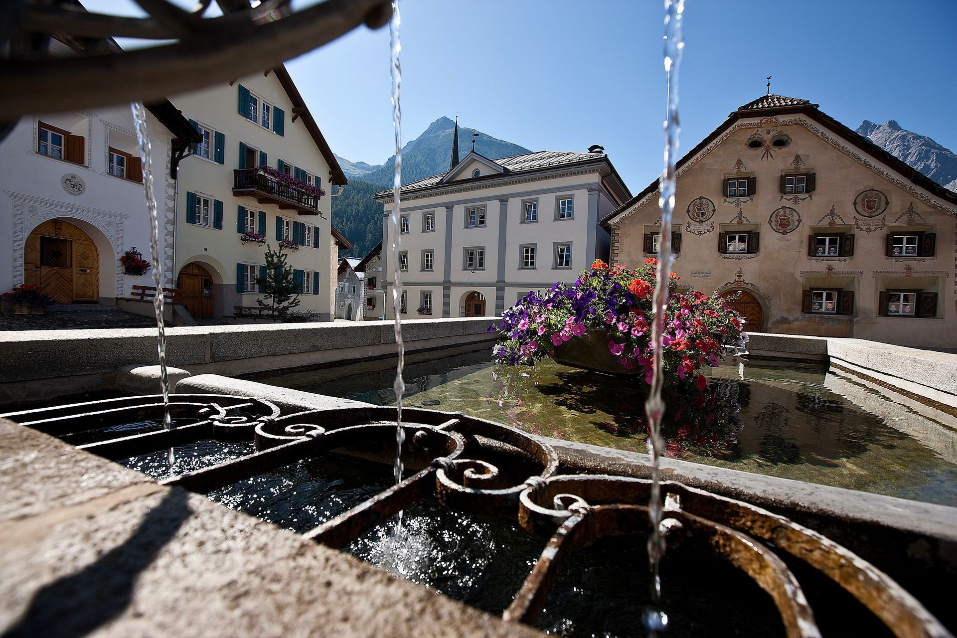 Ein Brunnen vor einem Gebäude mit einem Berg im Hintergrund