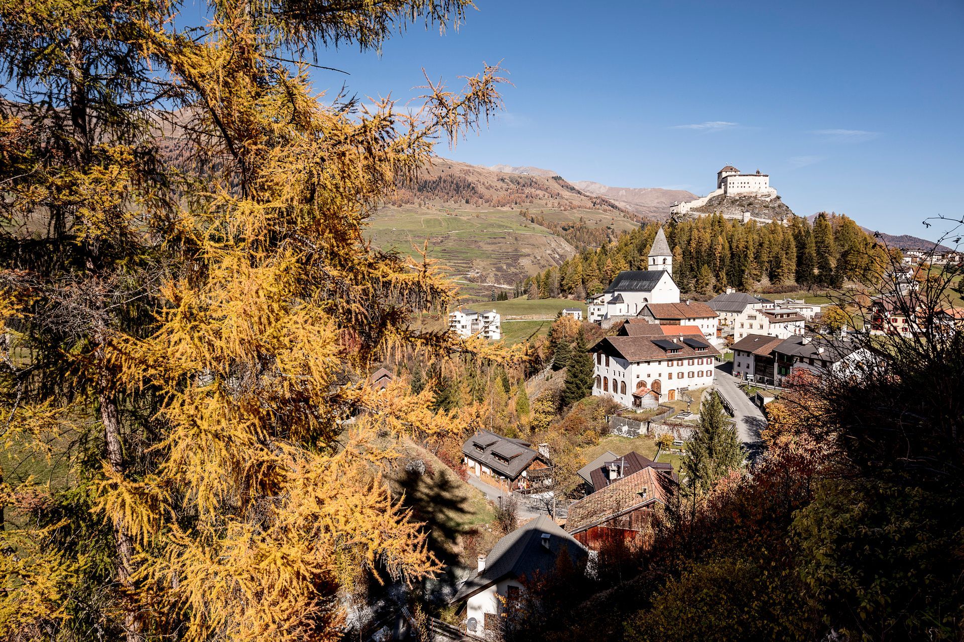 Ein kleines Dorf mit einer Burg auf einem Hügel im Hintergrund.