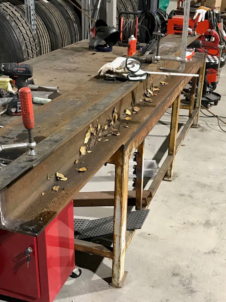 Teräksinen I-palkki kiinnitettynä työpajan työpöytään, jonka pinnalla on metallilastuja.