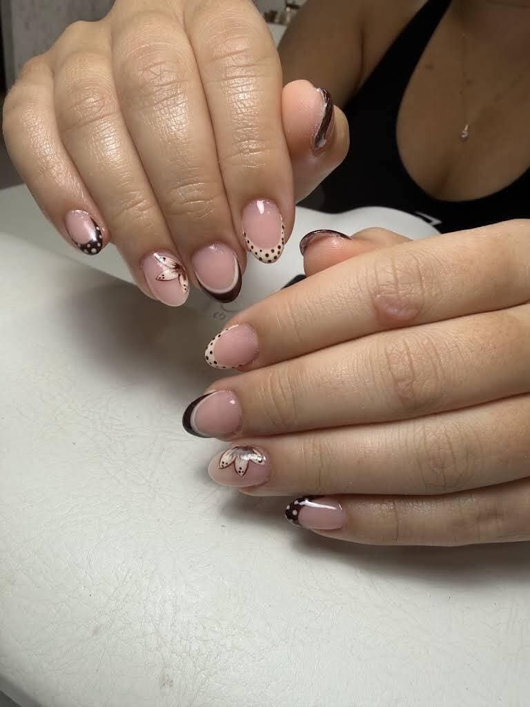 Manos con uñas de punta francesa con purpurina rosa descansando sobre una mesa.