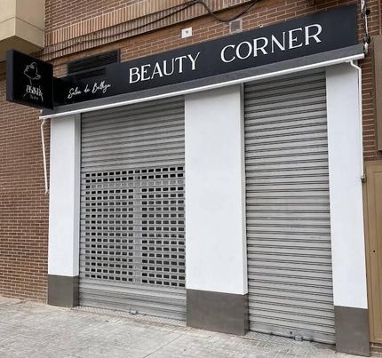 Local comercial cerrado con contraventanas grises y un letrero negro que dice 