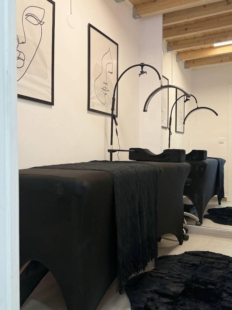 Puestos de peluquería negros con espejos y sillas en un interior minimalista.