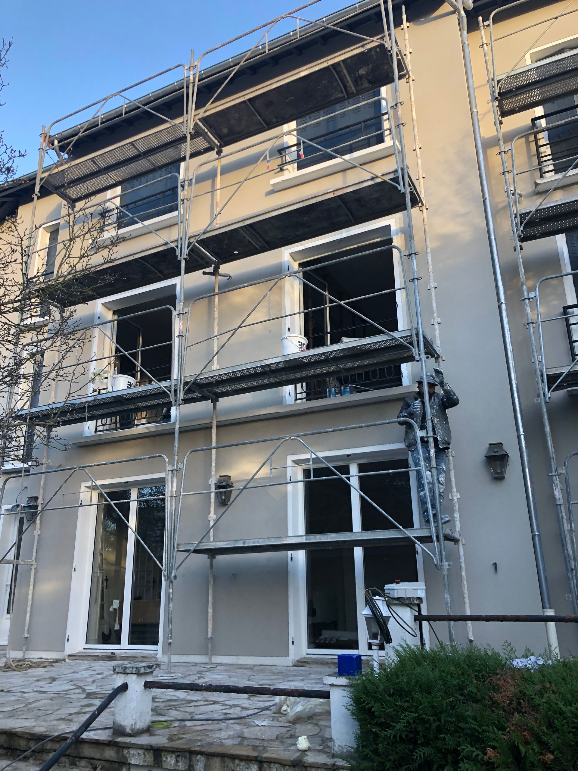 Façade grise du bâtiment en rénovation avec des échafaudages.