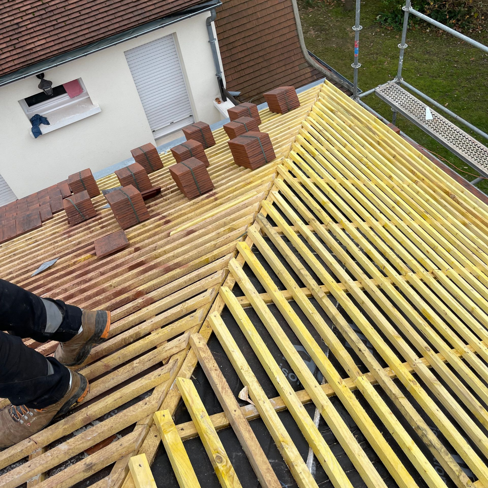 Toiture en construction avec charpente en bois et tuiles en briques.