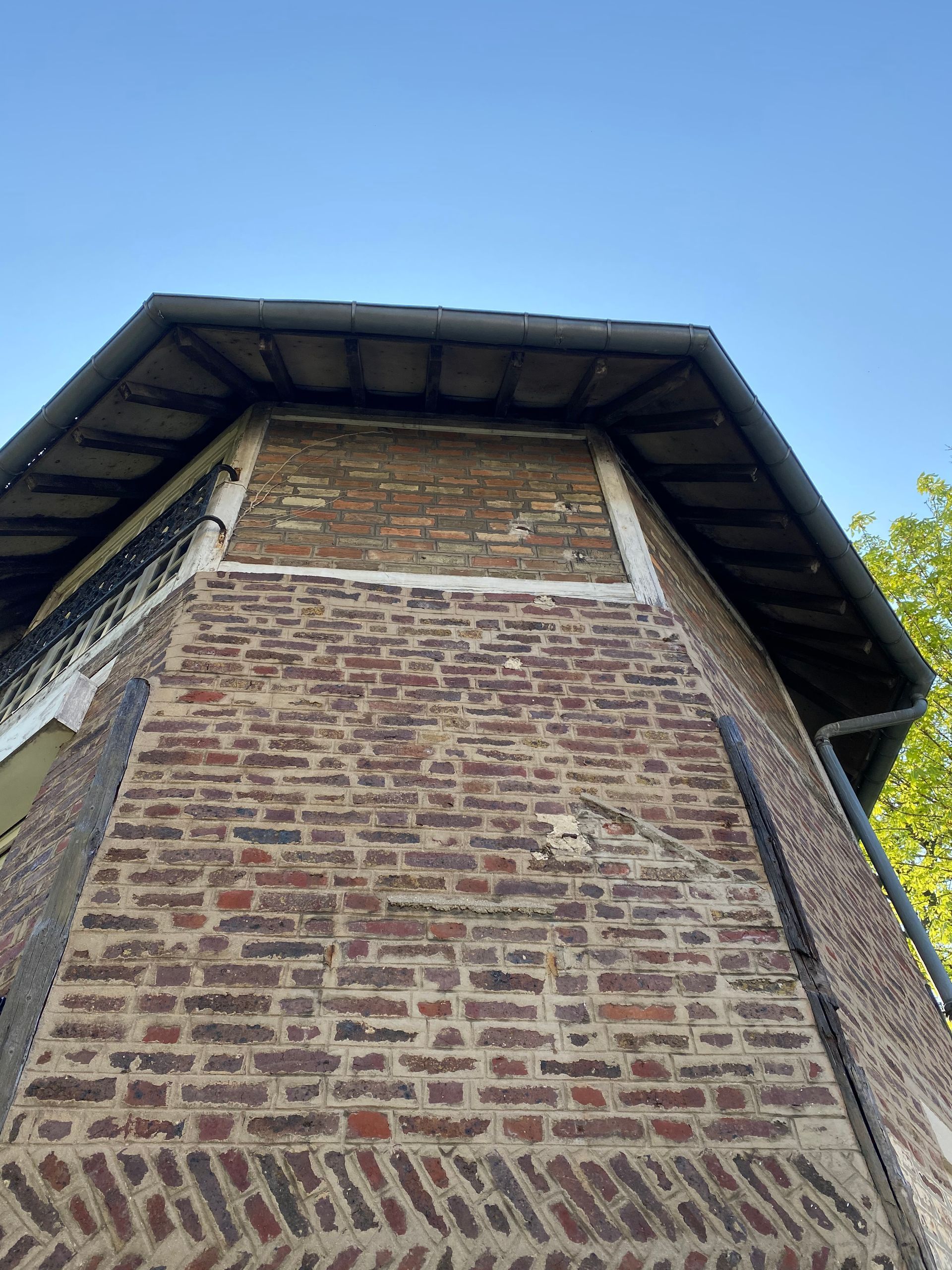 Tour en briques, toit sombre, sur fond de ciel bleu.