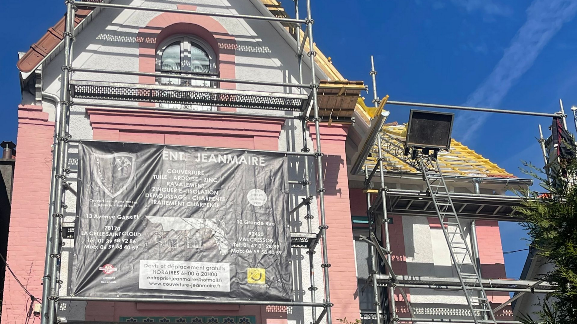 Façade rose et blanc d'un bâtiment avec échafaudages, en cours de rénovation.