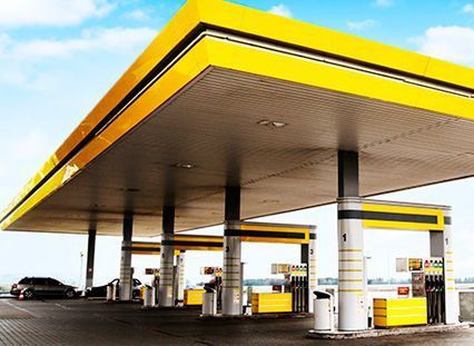 Una gasolinera amarilla con coches aparcados delante.