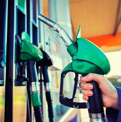 Una persona sostiene un surtidor de gasolina verde en una gasolinera.