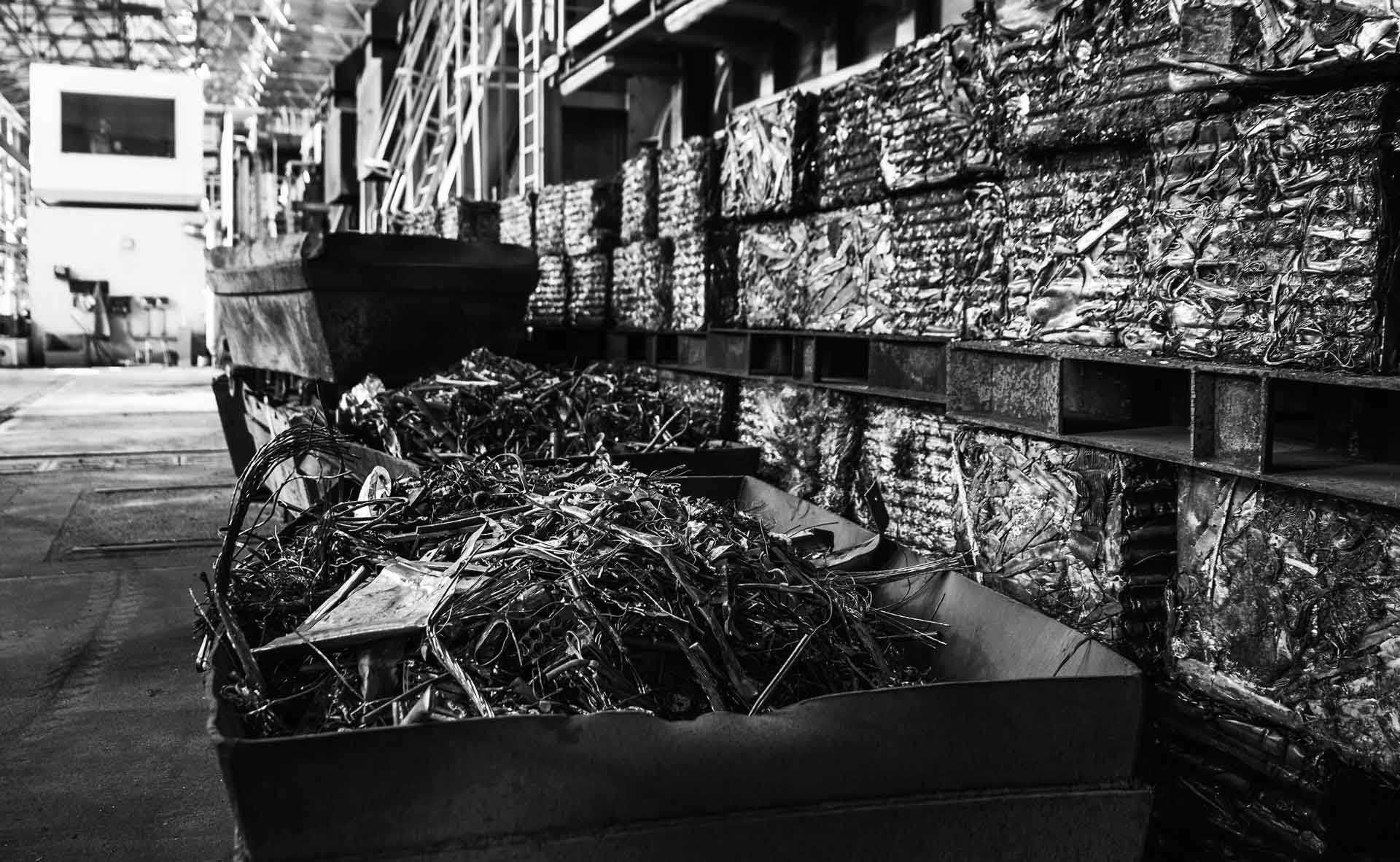 Bennes de déchets ferreux et étagères remplies de blocs de métaux compressés dans un entrepôt