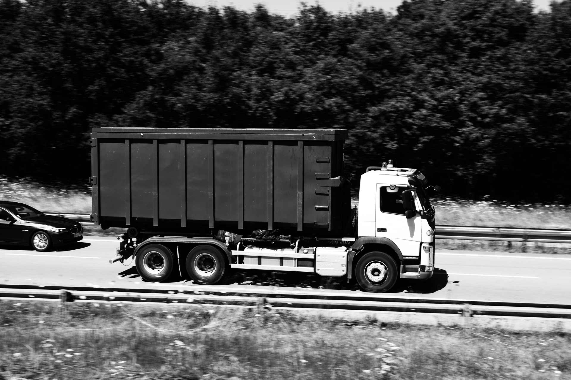 Un camion transportant une benne sur une voie rapide