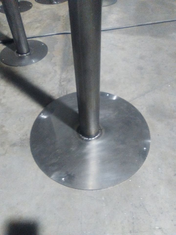 Una base de mesa de acero inoxidable reposa sobre un piso de concreto.