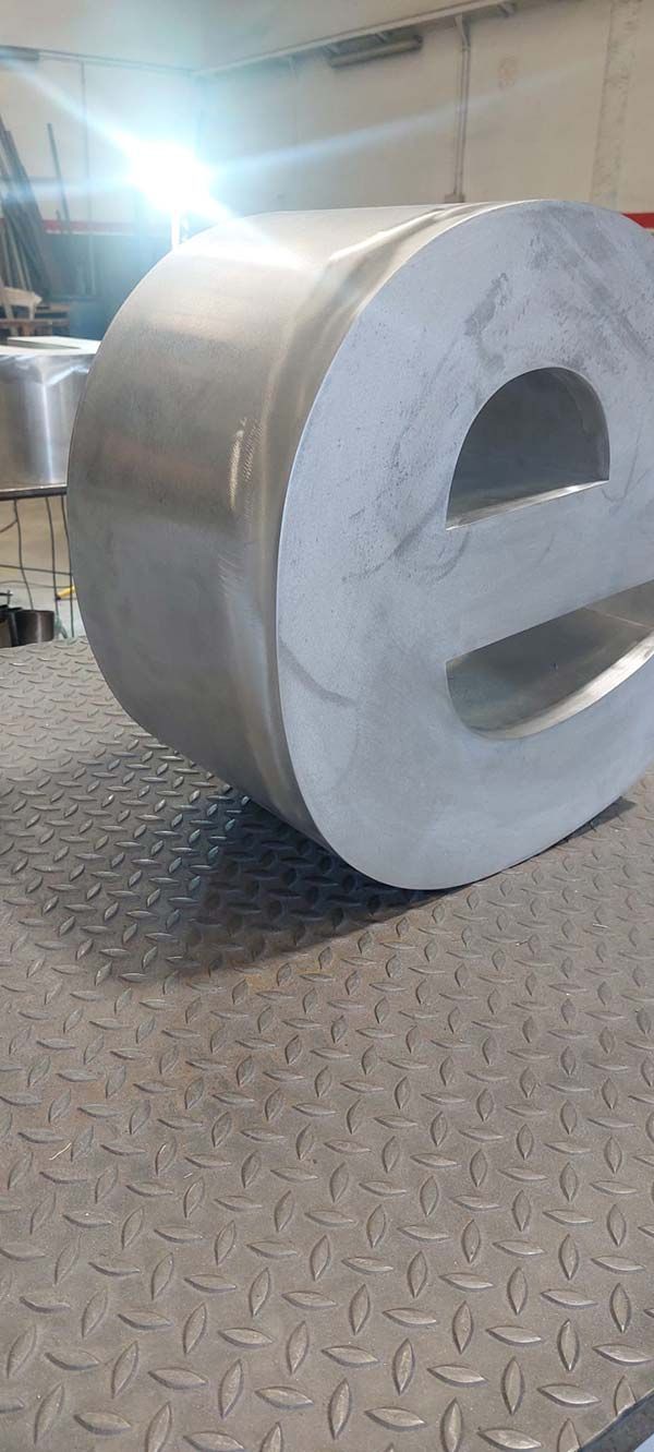 Gran cilindro industrial metálico con núcleo de espuma gris sobre un suelo de chapa estriada, en un entorno de taller.