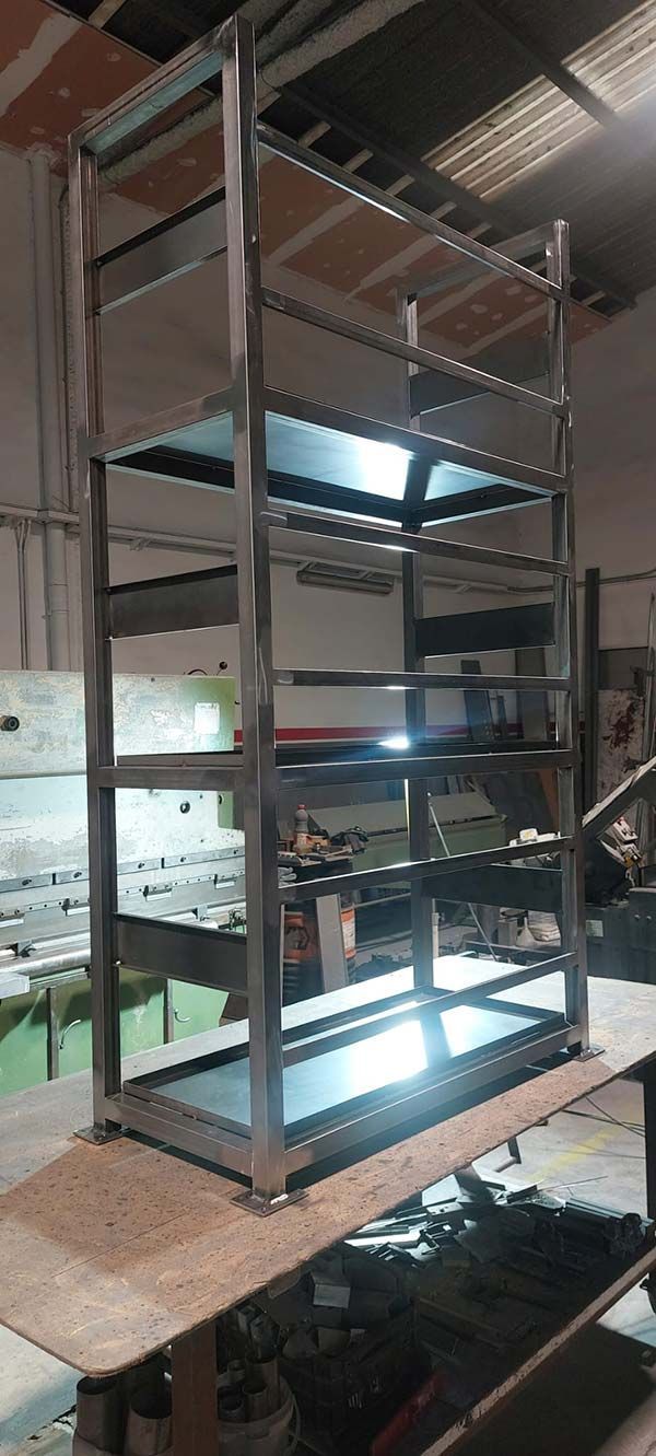 Estantería industrial metálica alta en un taller, con luces brillantes y equipos en los estantes inferiores.