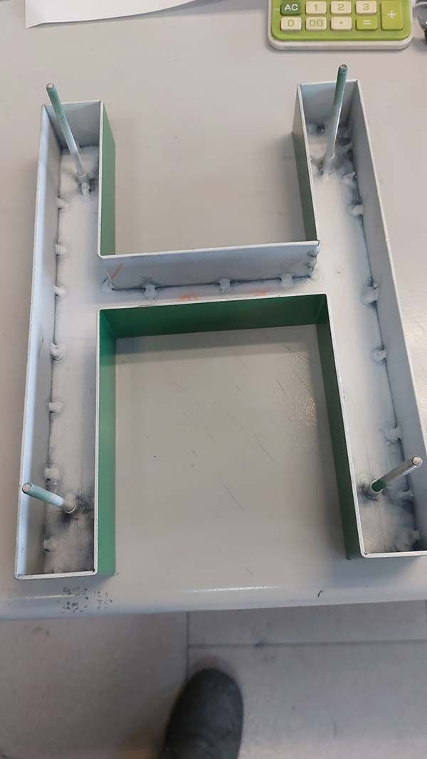 Maqueta de cartón blanco en forma de U con paredes interiores grises sobre una mesa, vista desde arriba.