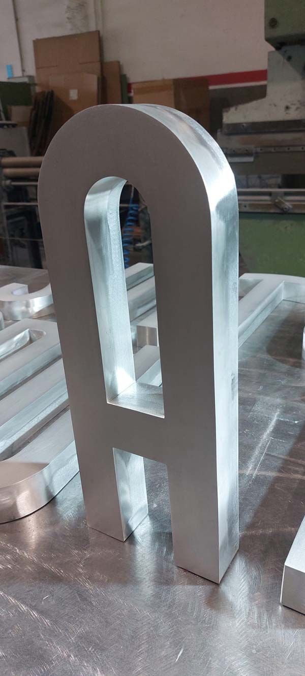 Objeto blanco con forma de arco, impreso en 3D, que se encuentra sobre una mesa de trabajo en un taller.