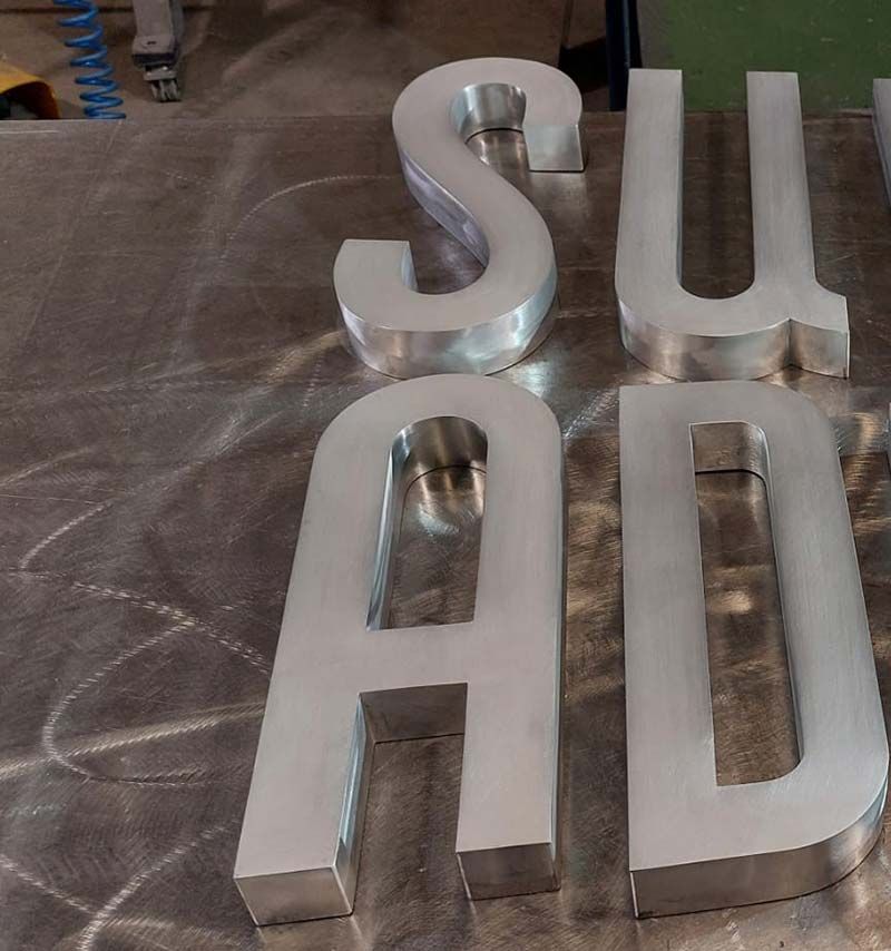 Letras plateadas en 3D sobre un banco de trabajo que forman la palabra 
