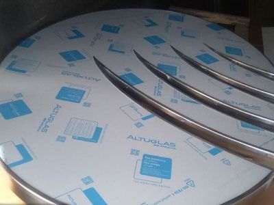 Una mesa redonda de acero inoxidable con láminas de acrílico sobre ella.
