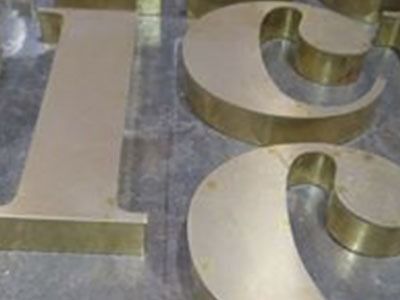 Un primer plano de una letra l y g de latón sobre una mesa.