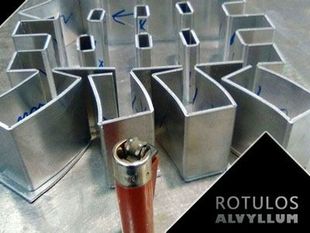Un encendedor rojo se encuentra junto a un montón de tubos de aluminio.