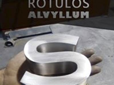 Una persona sostiene una letra s de acero inoxidable en su mano.