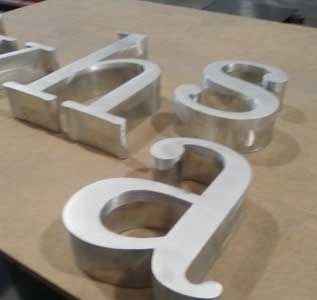 Las letras de aluminio están colocadas encima de una mesa de madera.