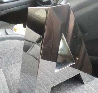 Una escultura de acero inoxidable está sentada en lo alto de una escalera de un automóvil.