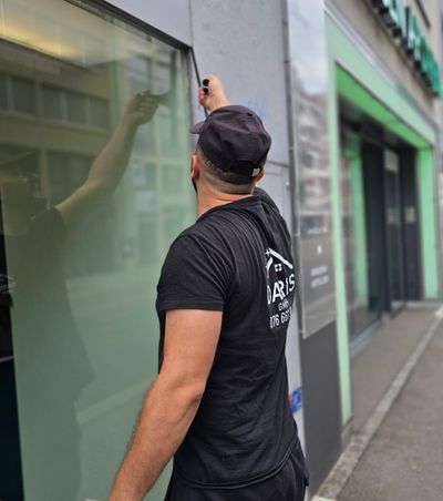 Mann in blauer Uniform befestigt eine Klimaanlage an einer weißen Wand; Innenaufnahme.