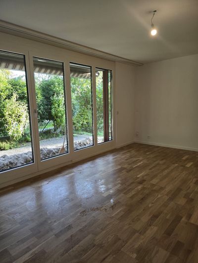 Person fegt einen Betonboden mit einem Besen, im Hintergrund eine Schaufel.