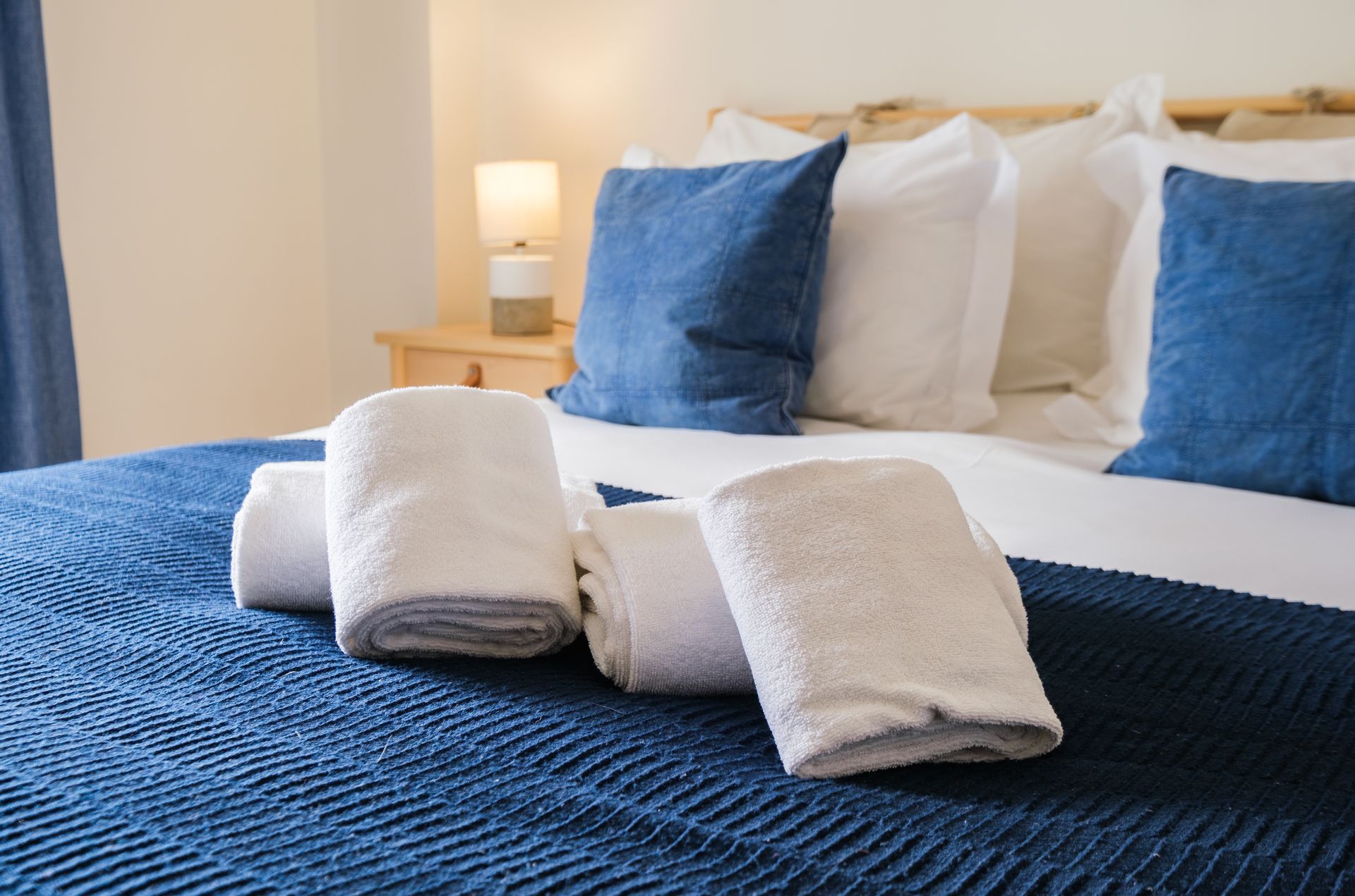 A bed with blue and white pillows and towels on it.